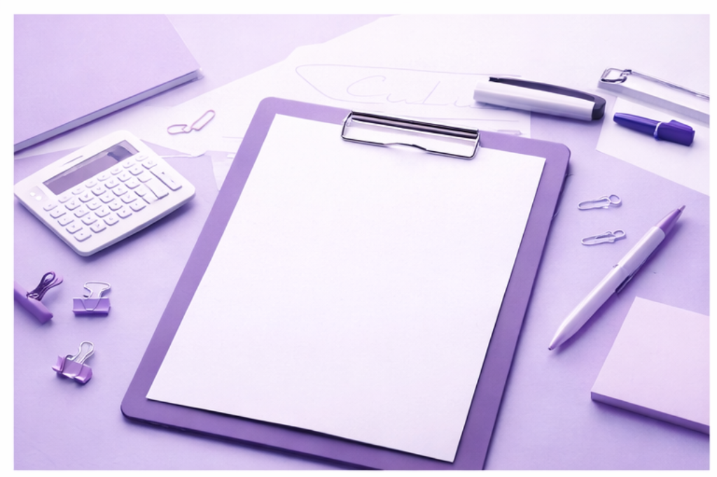 Desk with purple clipboard holding a blank sheet of white paper, calculator, pens, paper clips, fetish, stapler, and sticky notes, all with a purple color theme.