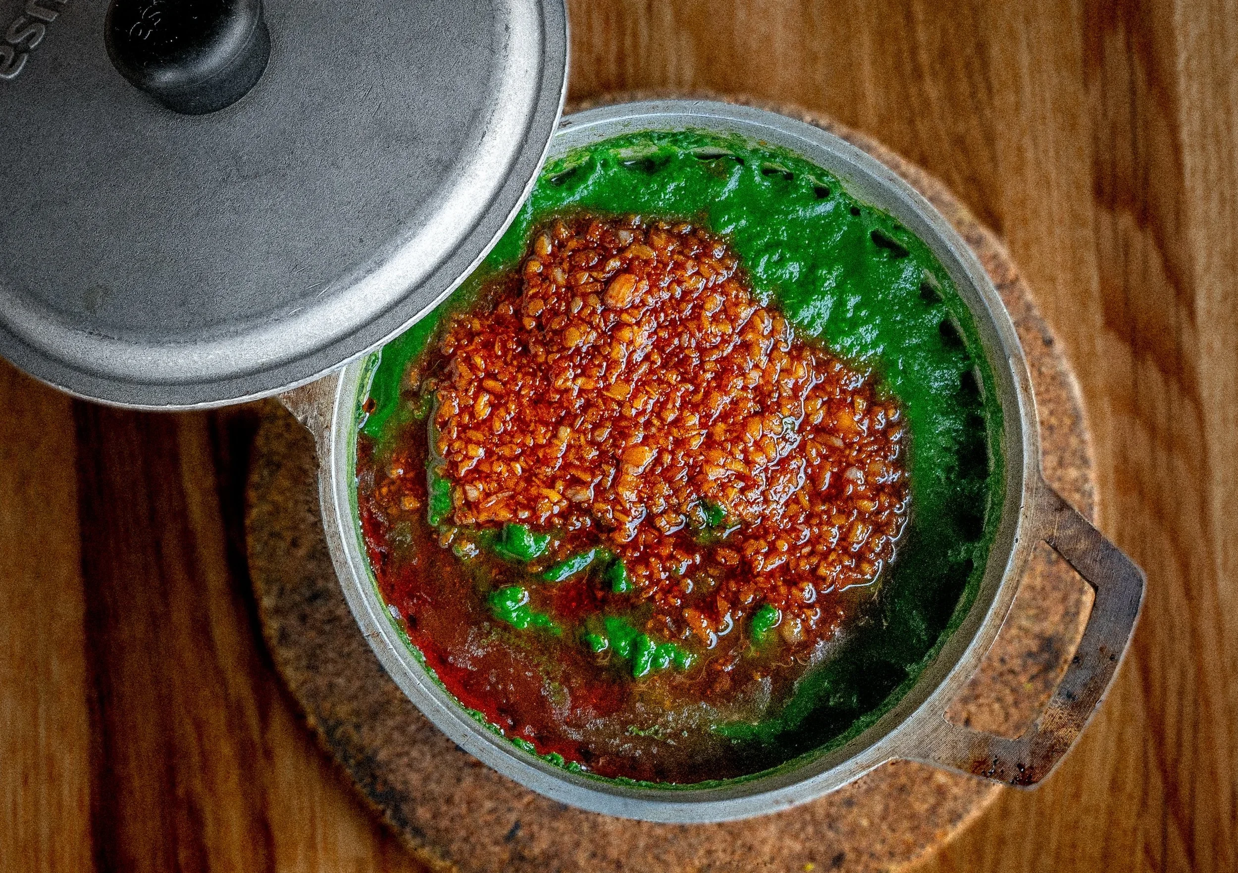 A metal container with a black lid is partially open, revealing a mixture of colorful seasoning.