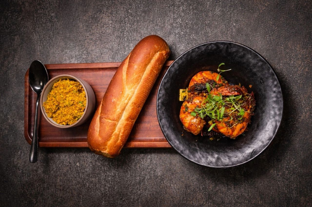 A black plate with grilled shrimp garnished with microgreens.