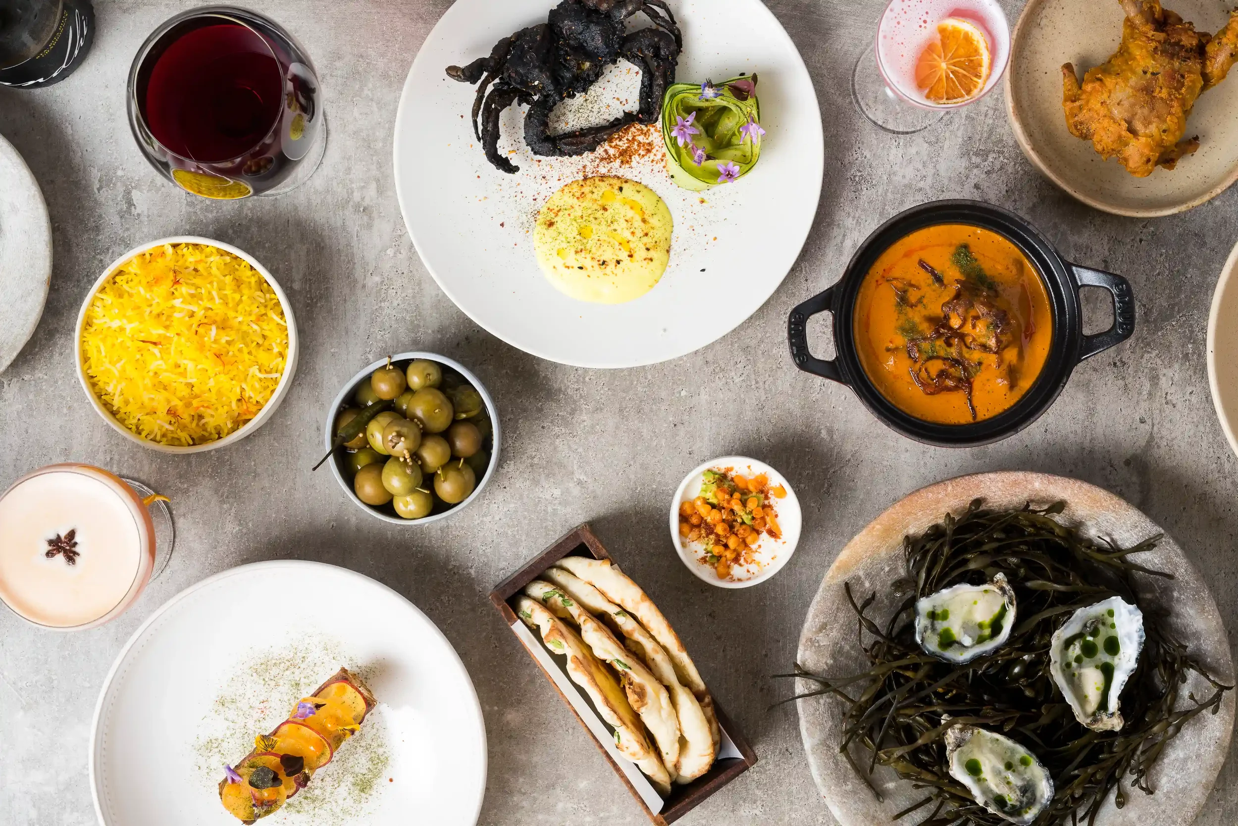 A variety of dishes, including rice, grilled meats, curry, vegetables, pickles, and drinks.