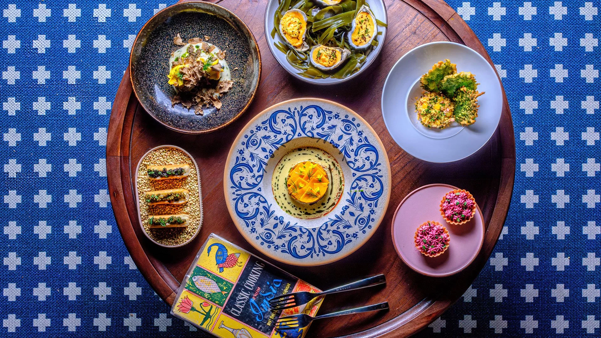 Assorted traditional Asian dishes on a round wooden tray, including egg salad.