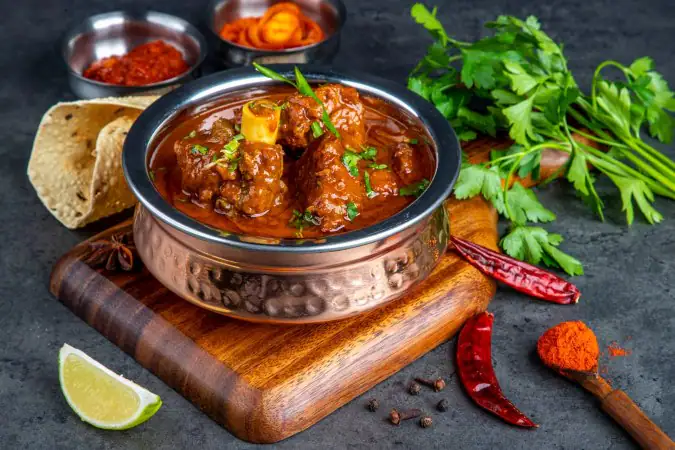 A bowl of Indian-style spiced meat curry garnished with cilantro