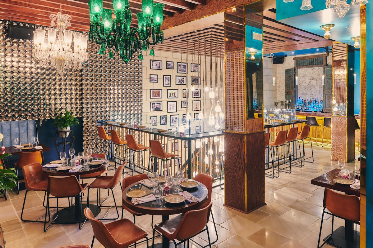 Upscale restaurant interior with round tables set with plates, glasses, and cloth napkins.