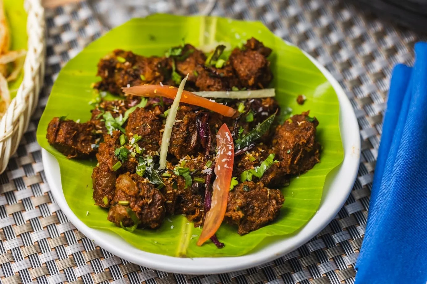 Plate of spicy Indian-style meat curry with vegetables.
