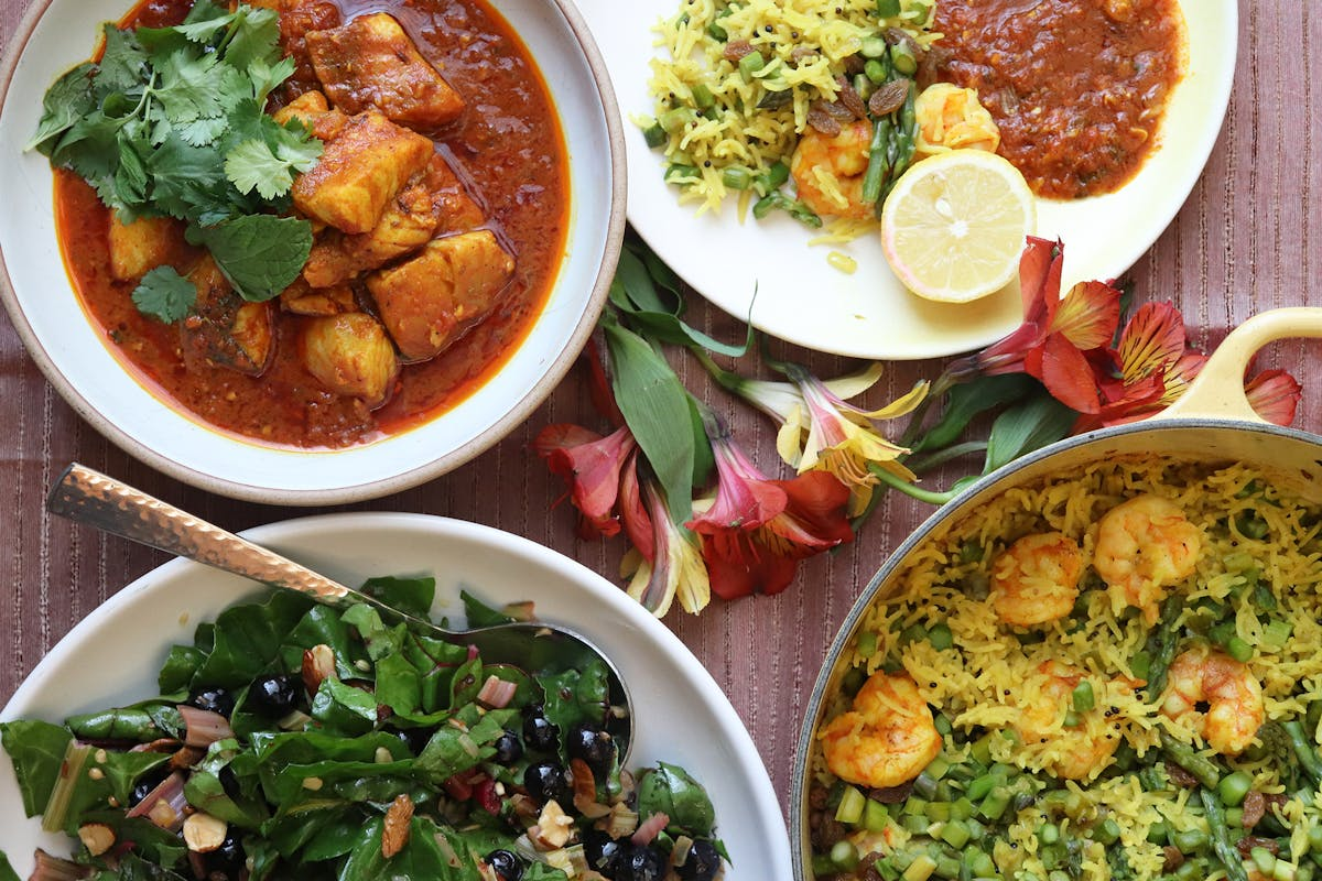 An assortment of Indian dishes including a bowl of potato curry with cilantro