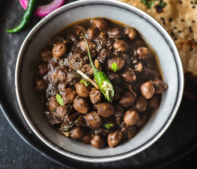Close-up of a bowl of cooked chickpeas in dark sauce
