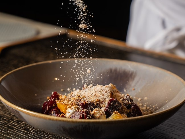 A bowl of mixed fruit dessert topped with grated cheese or powdered sugar