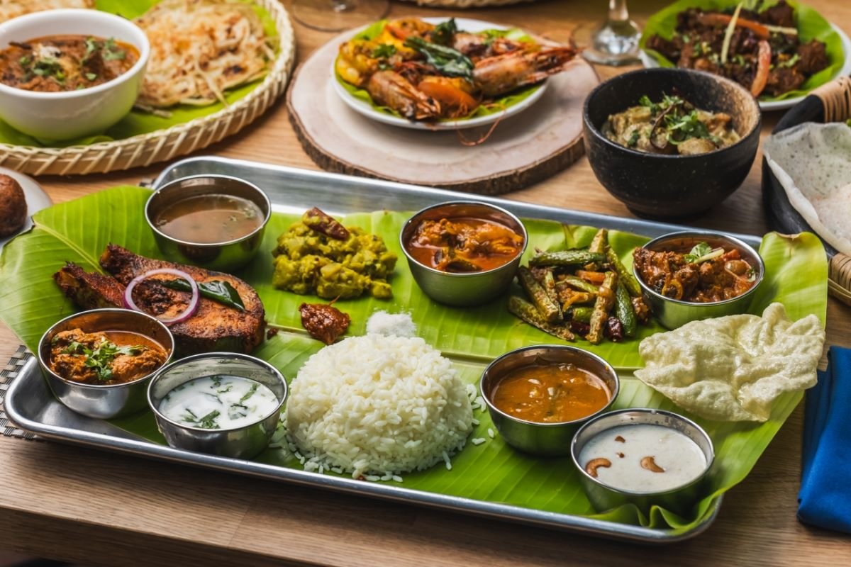 Assorted Indian cuisine dishes served on a banana leaf and in bowls.