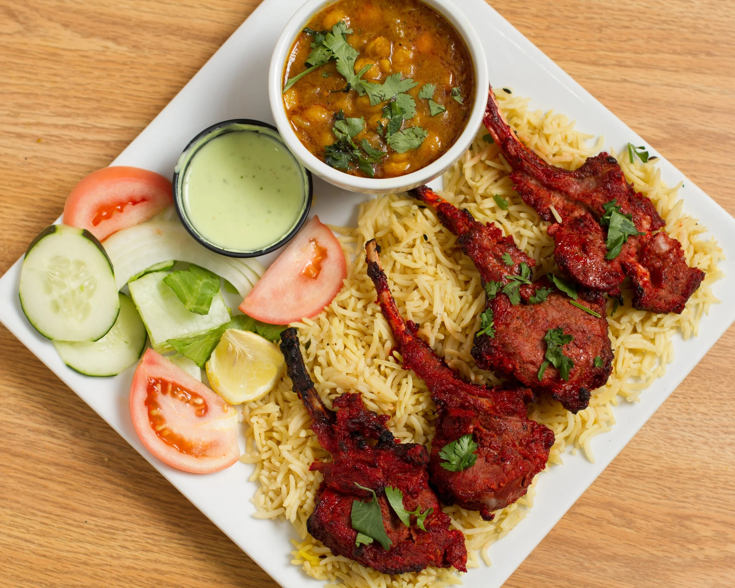 A white plate with an Indian meal containing spiced rice