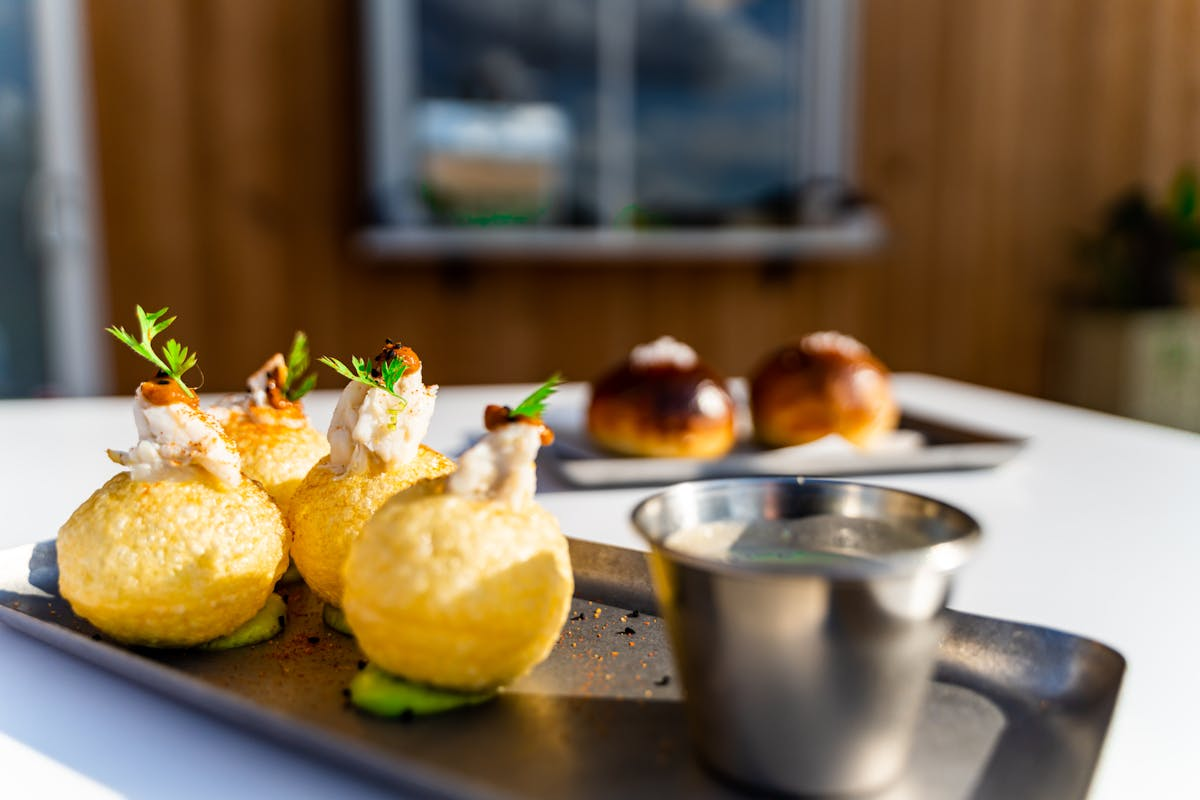 Close-up of fried appetizers garnished with herbs, with a dipping sauce