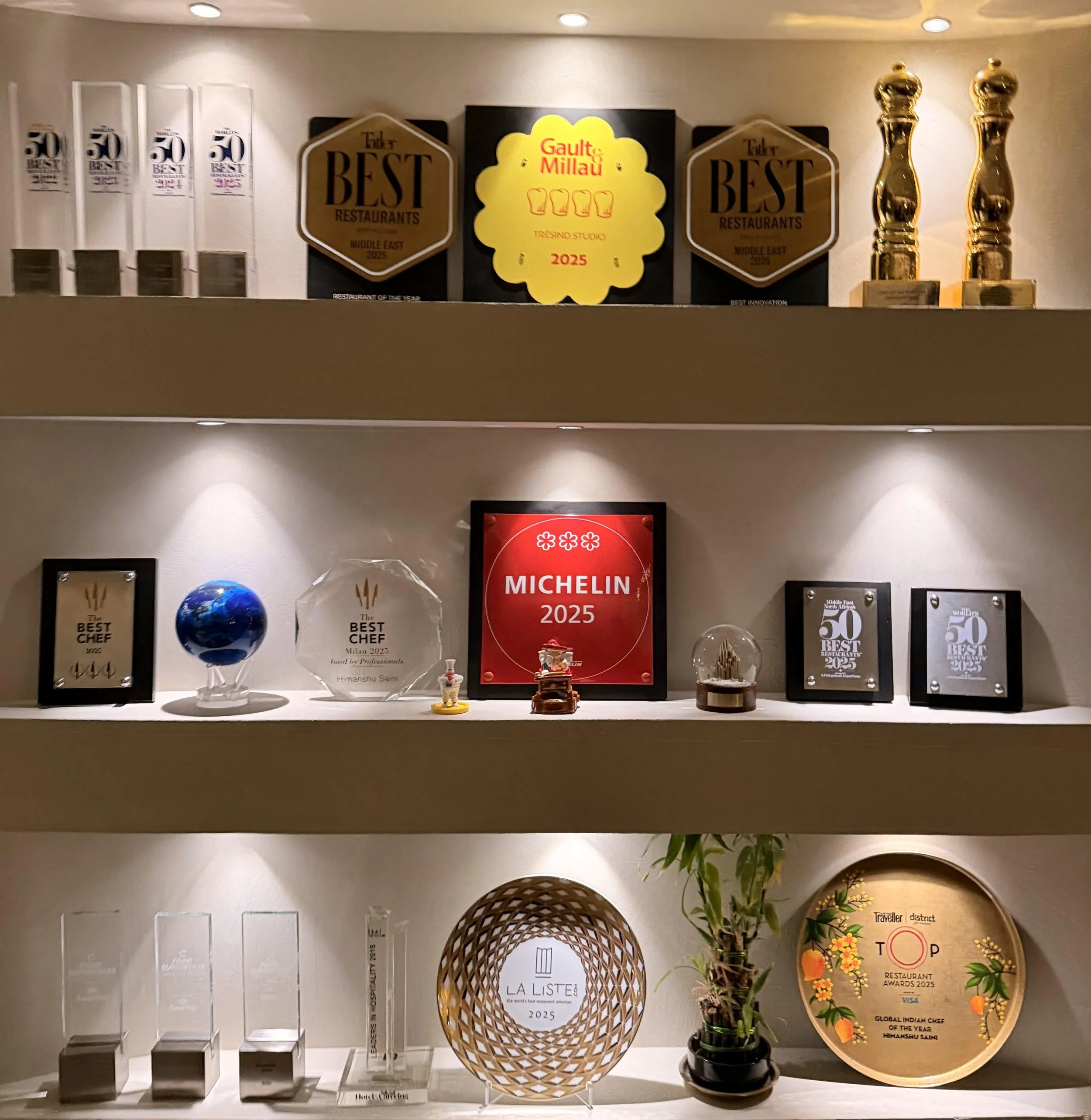 desi food reviews - display of multiple awards and recognitions including Michelin 2025, Top Restaurant Awards 2025, and The List 2025, with plaques, trophies, and a flower vase at Tresind Studio, Dubai.