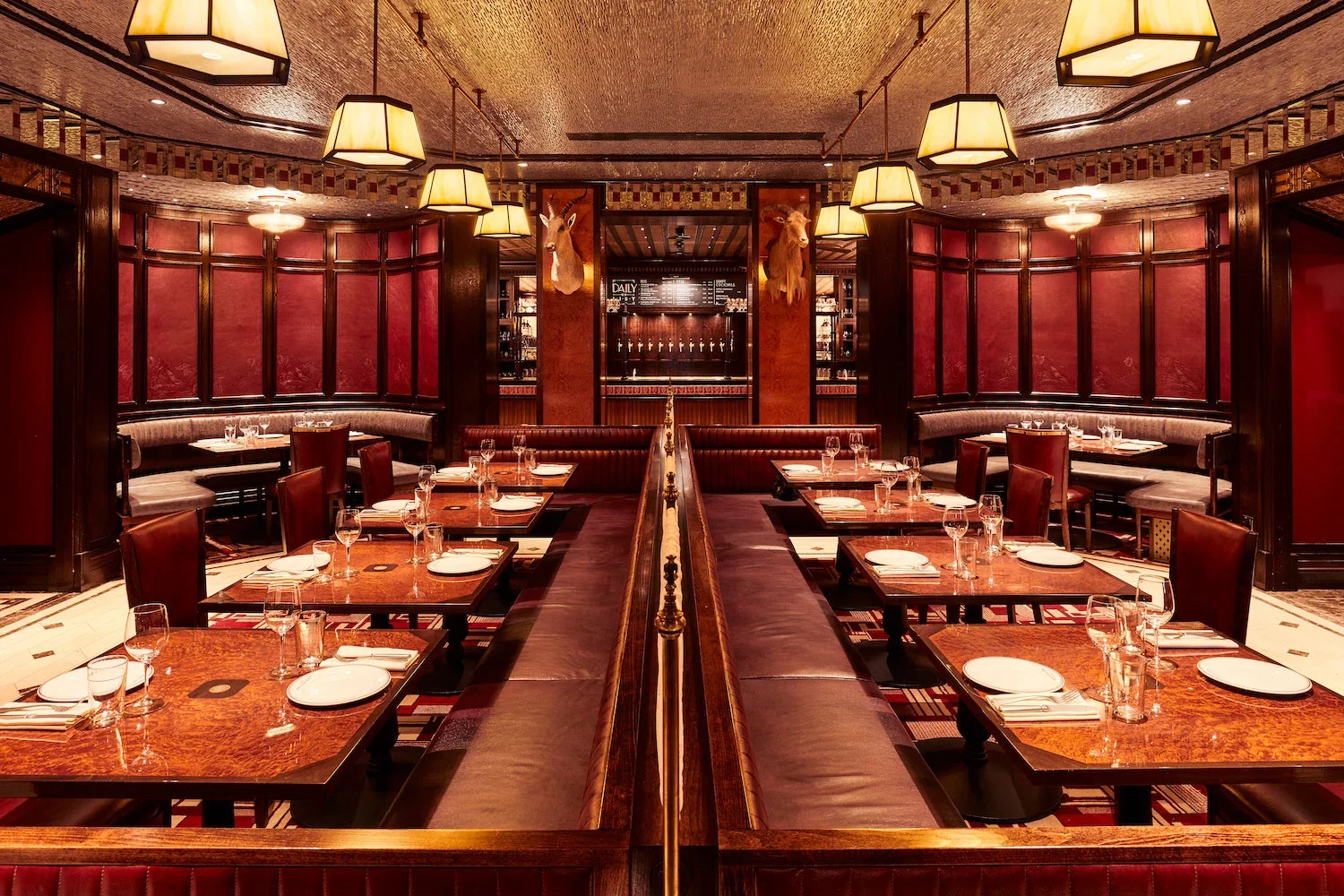 A restaurant with wooden tables, chairs, and booths, set with plates and glasses.
