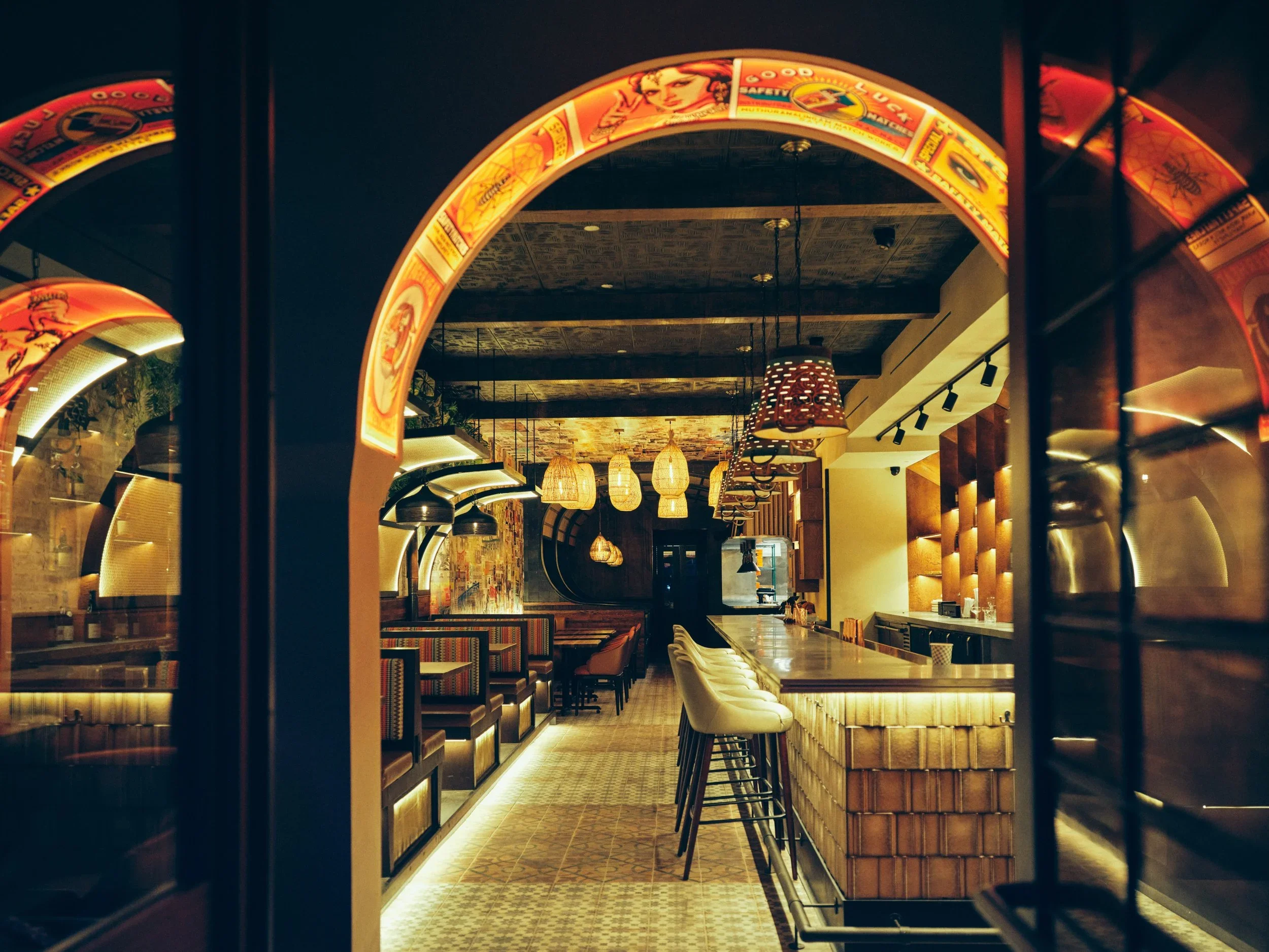 Interior of a modern restaurant or cafe with a bar counter, and decorative hanging lights.