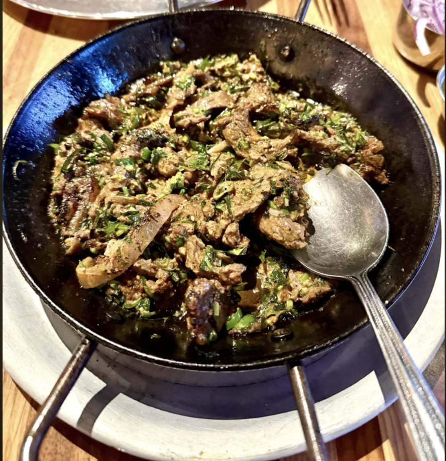 desi food reviews - A cast iron skillet filled with stir fried wagyu beef in new york city