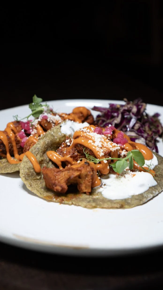 Plate of Mexican food with a taco topped with orange sauce