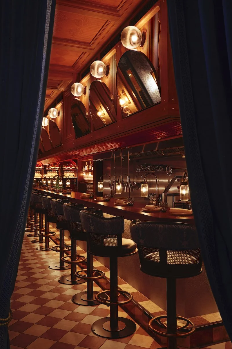 best south asian restaurants - A dimly lit upscale bar with a wooden counter, and high-back bar stools