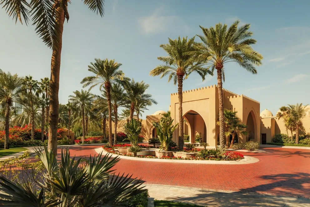 A luxurious courtyard with palm trees, and a red brick circular driveway
