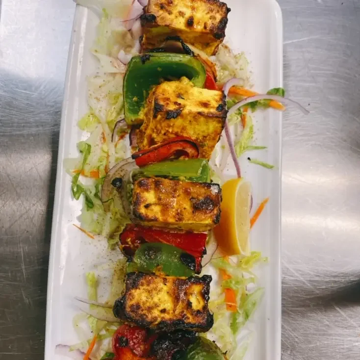 Grilled paneer and vegetable skewers served with lemon wedge