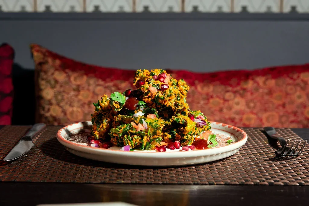 A plate of Indian vegetarian dish garnished with pomegranate seeds and herbs