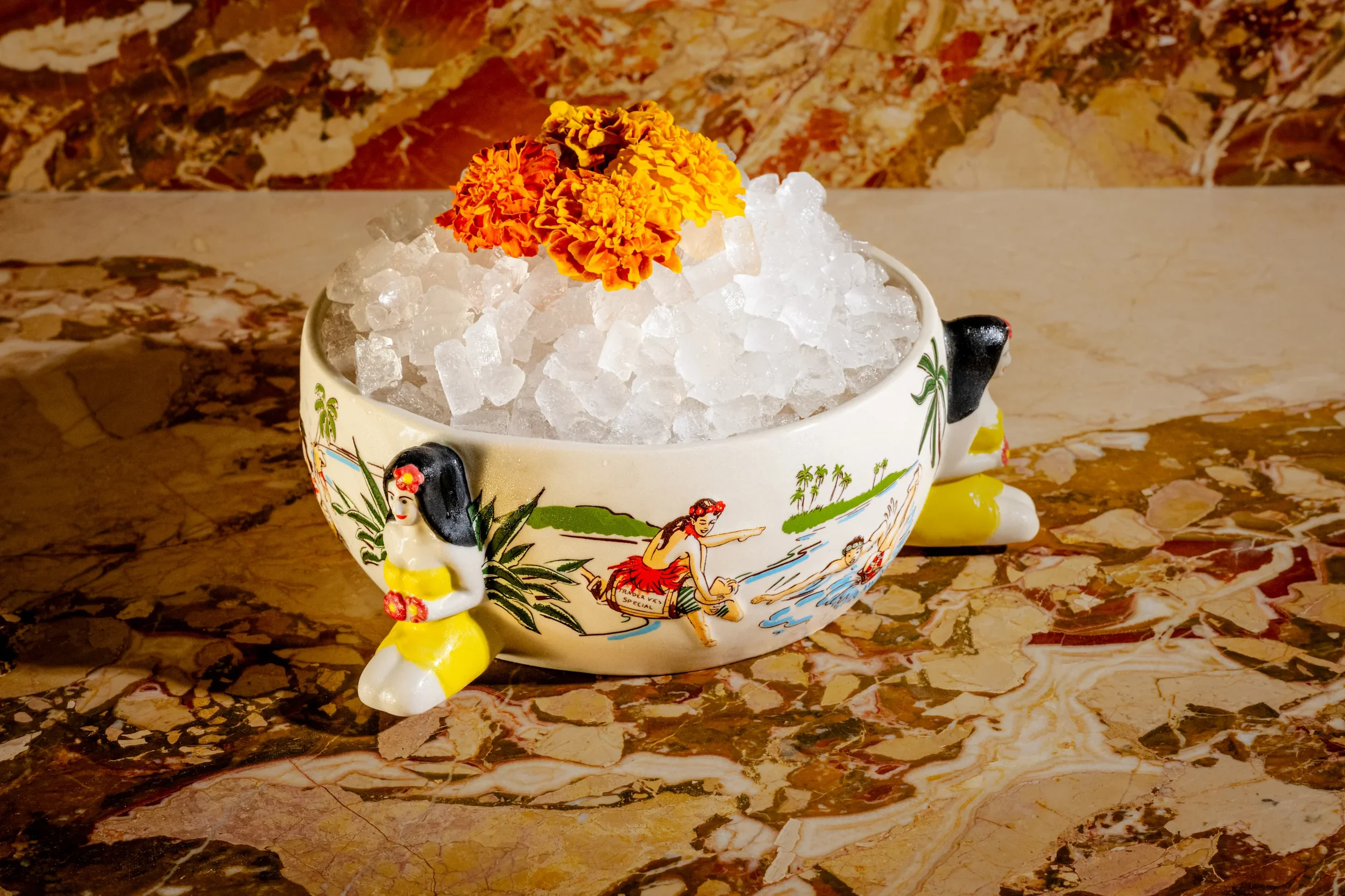 A decorative bowl filled with ice cubes with marigold flowers on top.