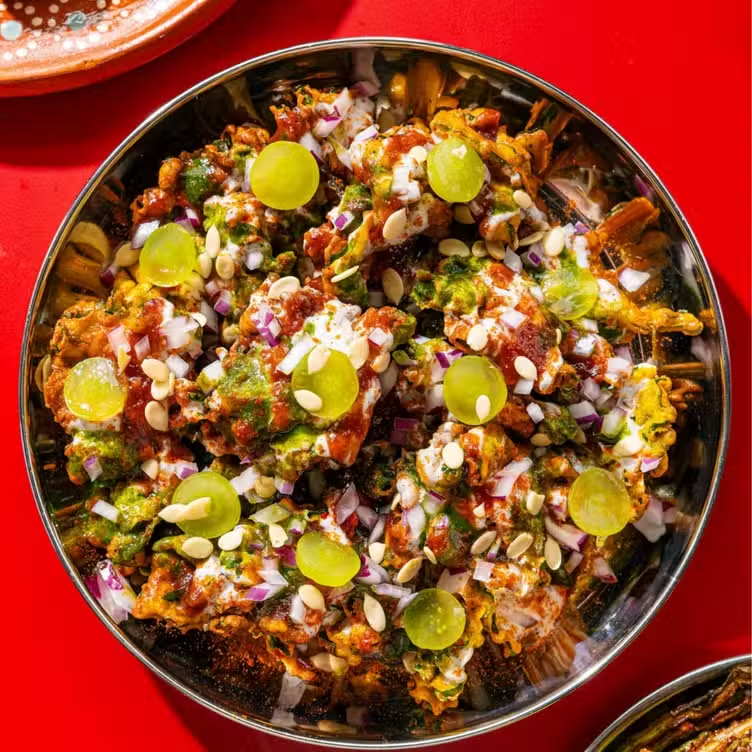 Close-up of a bowl of loaded nachos topped with diced red onions