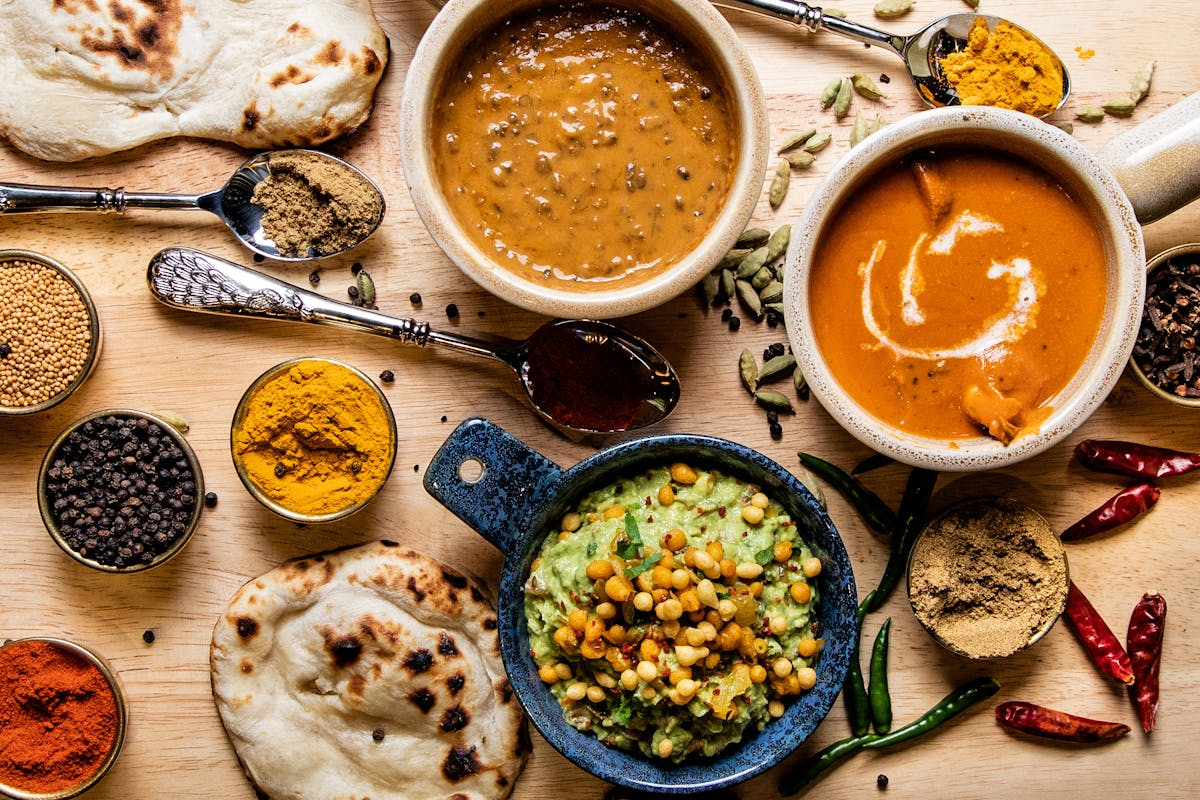 A variety of Indian dishes including lentil soup, vegetable curry, and naan bread.