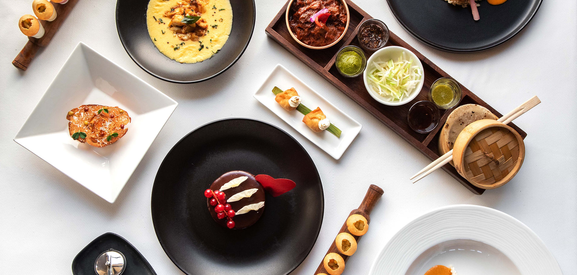 A variety of plated Asian dishes including sushi, curry, dumplings, and desserts.