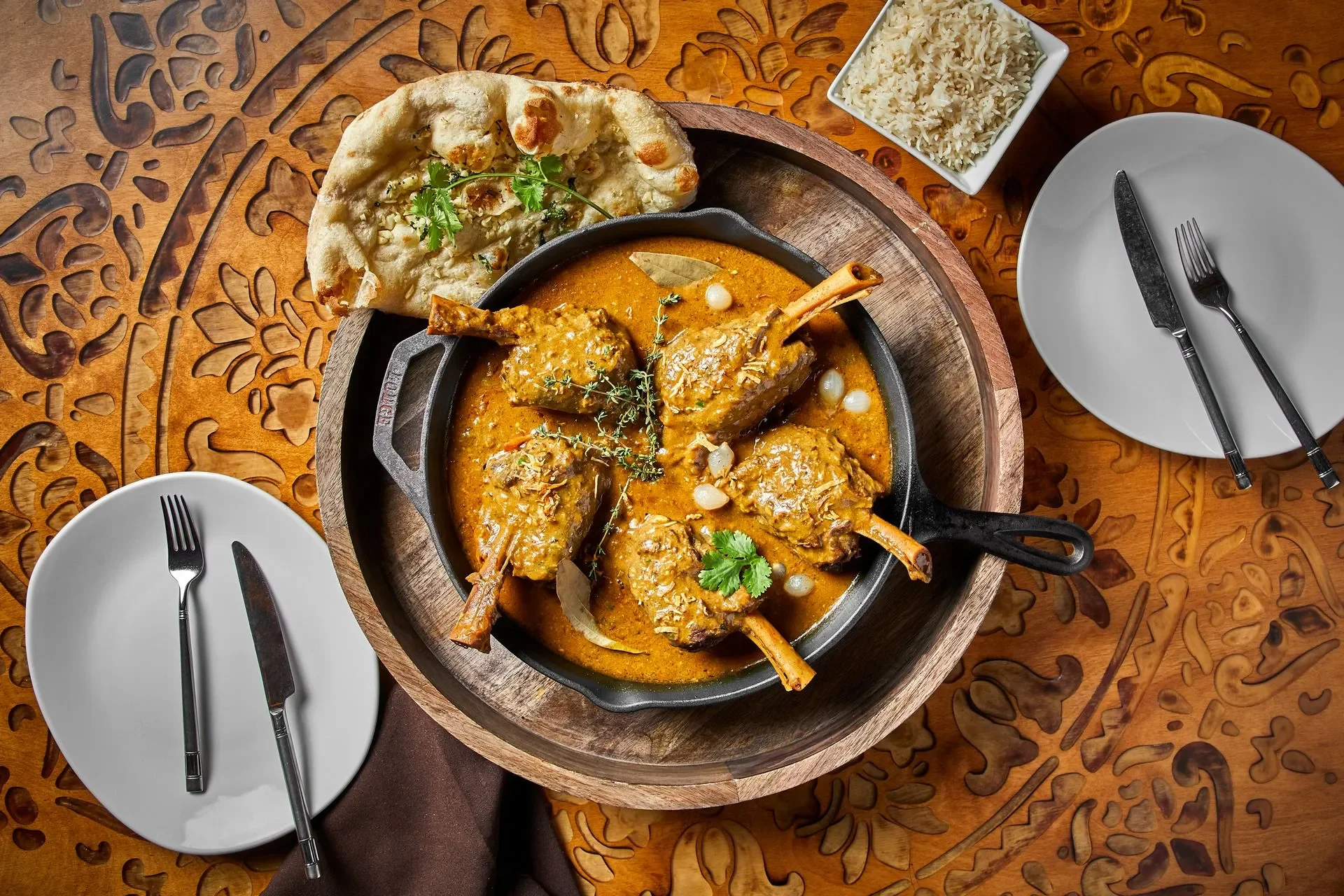 A top-down view of Indian lamb curry served in a black skillet
