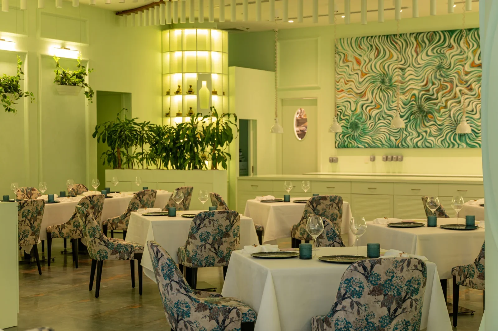 Interior of a restaurant with floral upholstered chairs, white tablecloth-covered tables