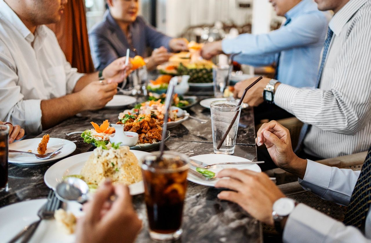 A group of people sitting around a table eating a meal with various dishes.