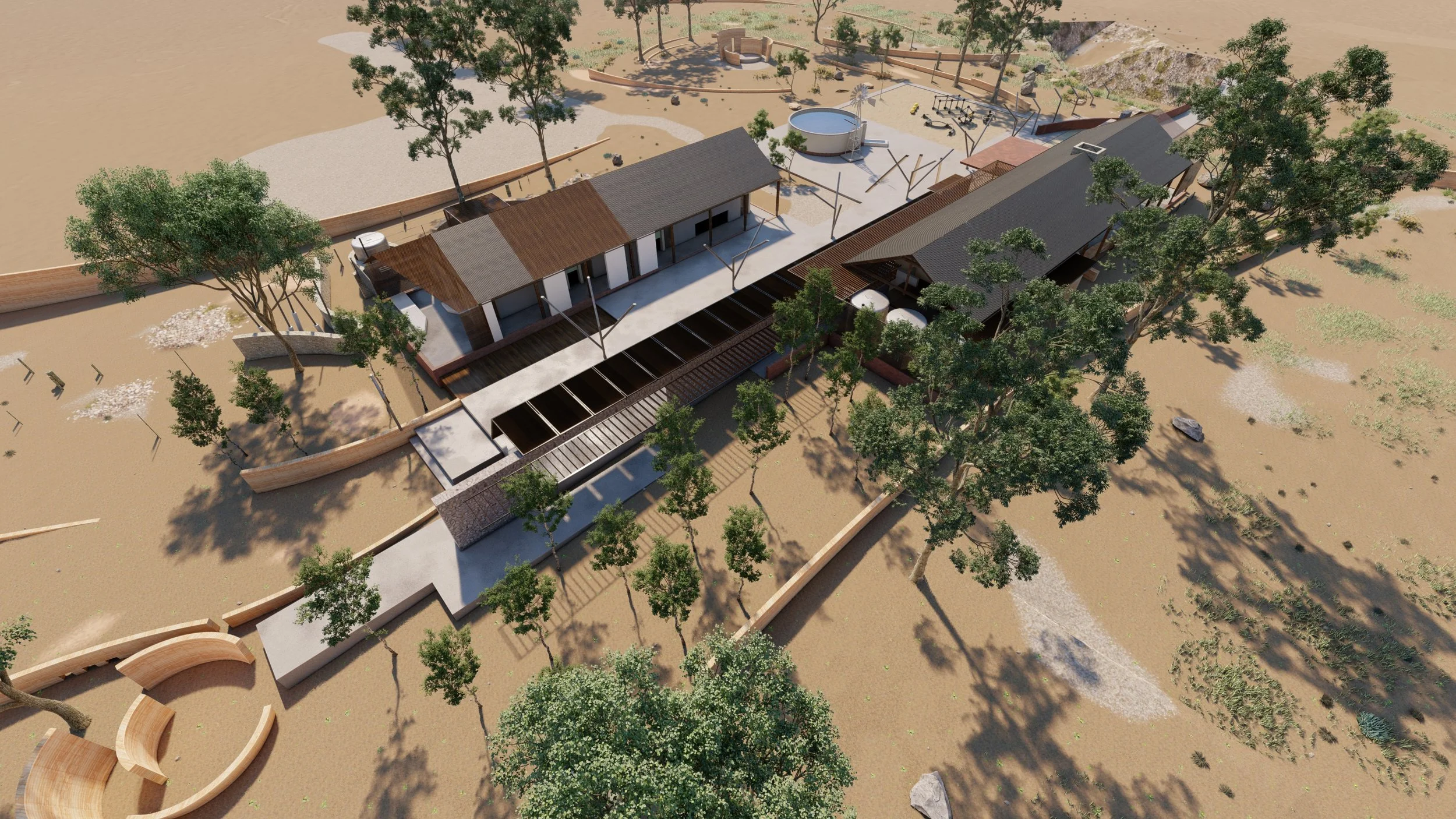 Aerial view of a modern outdoor recreational area with buildings, pathways, trees, and playground equipment in a sandy landscape.