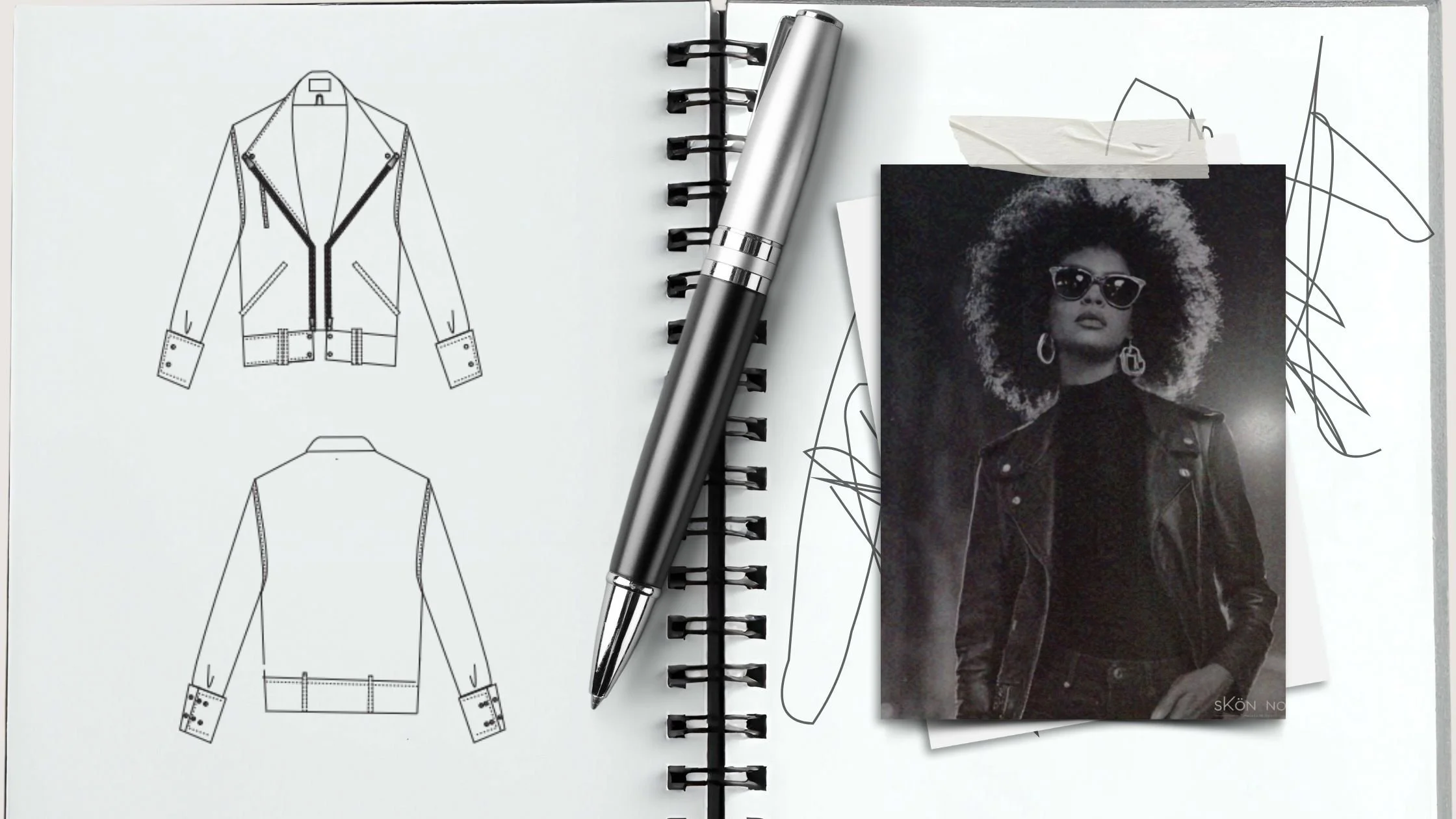 A notebook with fashion sketches of a leather jacket, a pen placed diagonally on it, and a black-and-white photo of a woman wearing sunglasses, a leather jacket, and earrings, partially taped to the page with crumpled paper at the top.