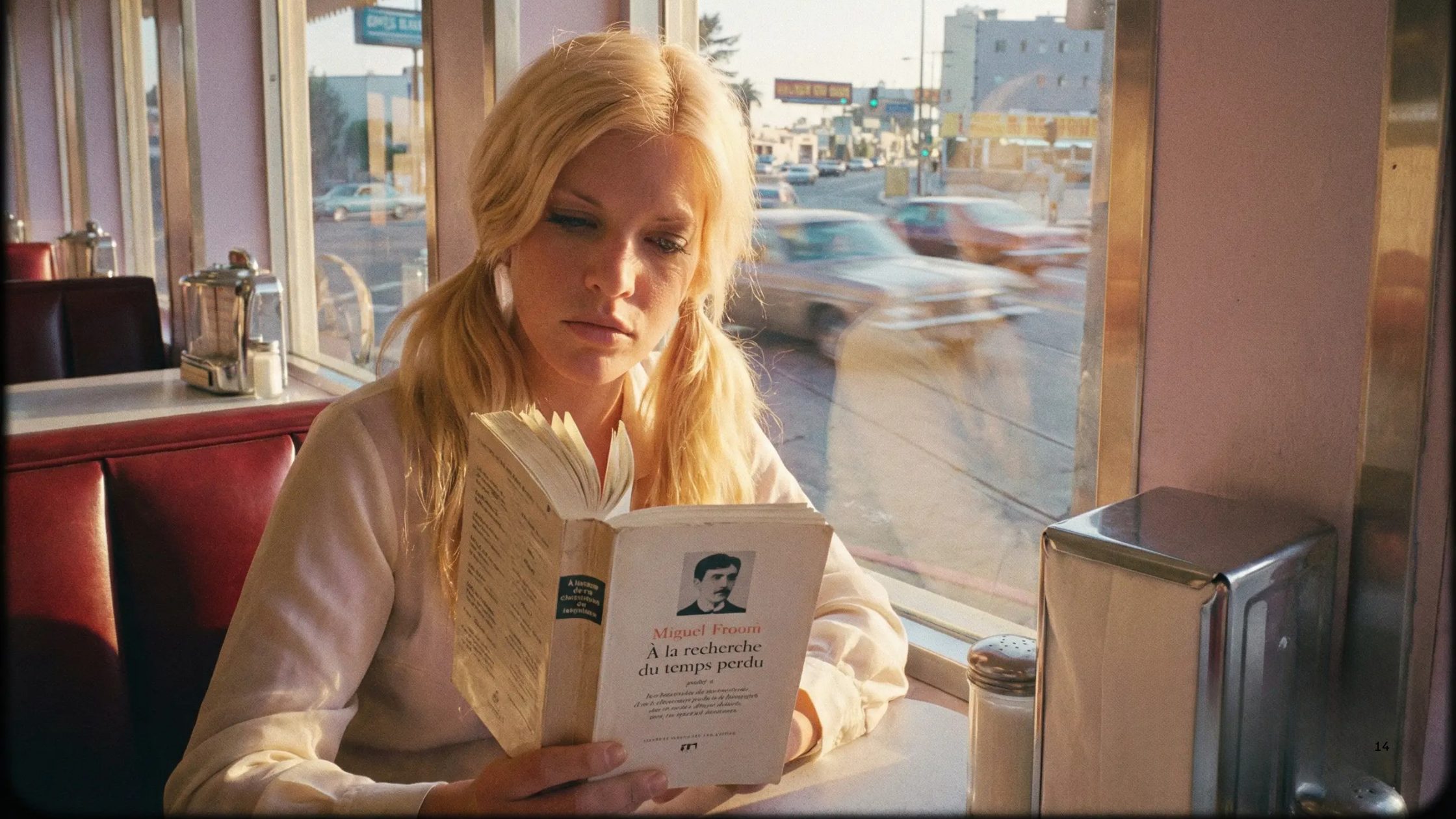 A woman with blonde hair sitting in a diner, reading a book titled 'À la recherche du temps perdu' by Marcel Proust near a window overlooking a busy street.