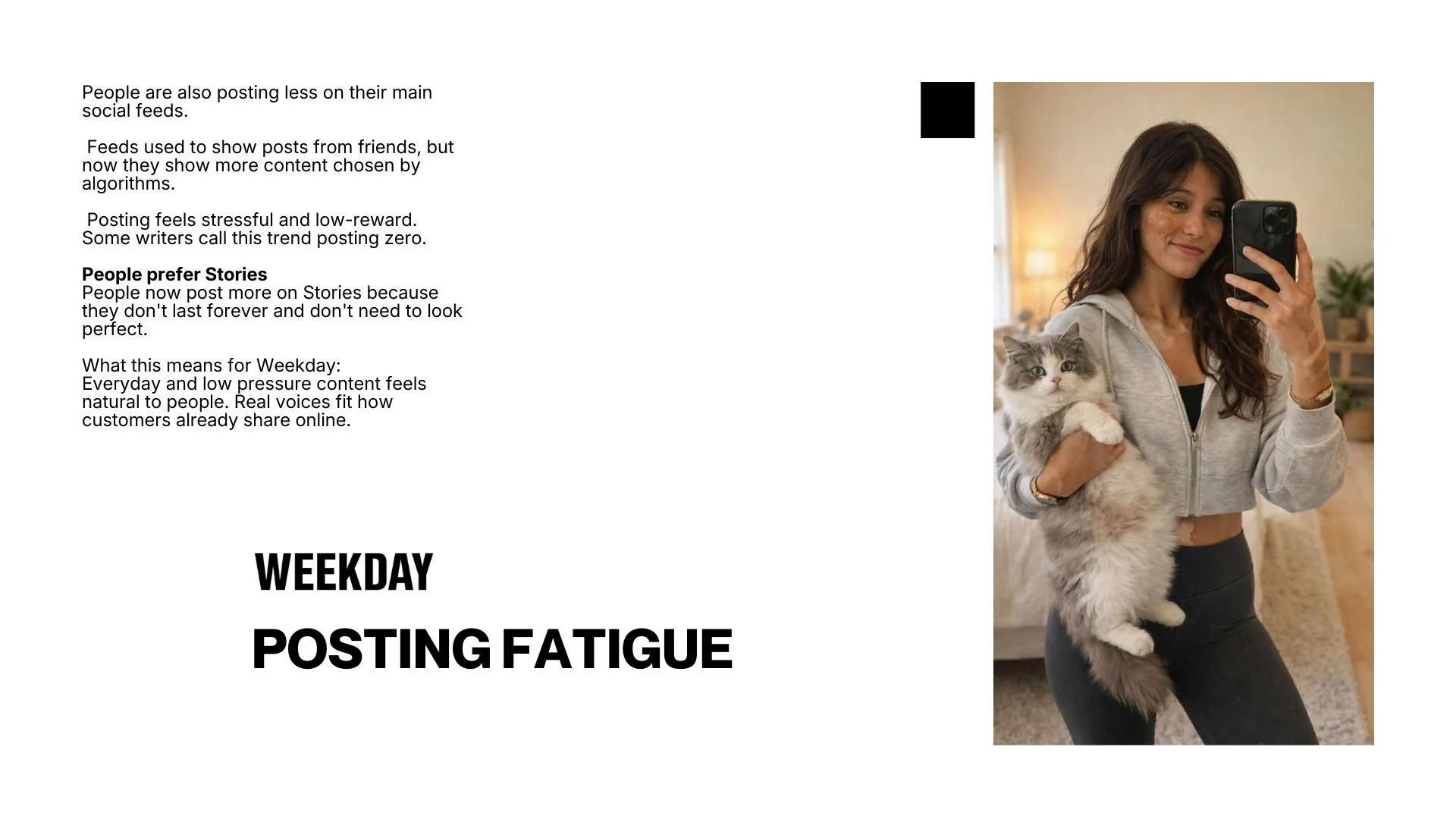 A woman taking a mirror selfie in a cozy living room, holding a fluffy gray and white cat, with soft lighting and warm decor in the background.