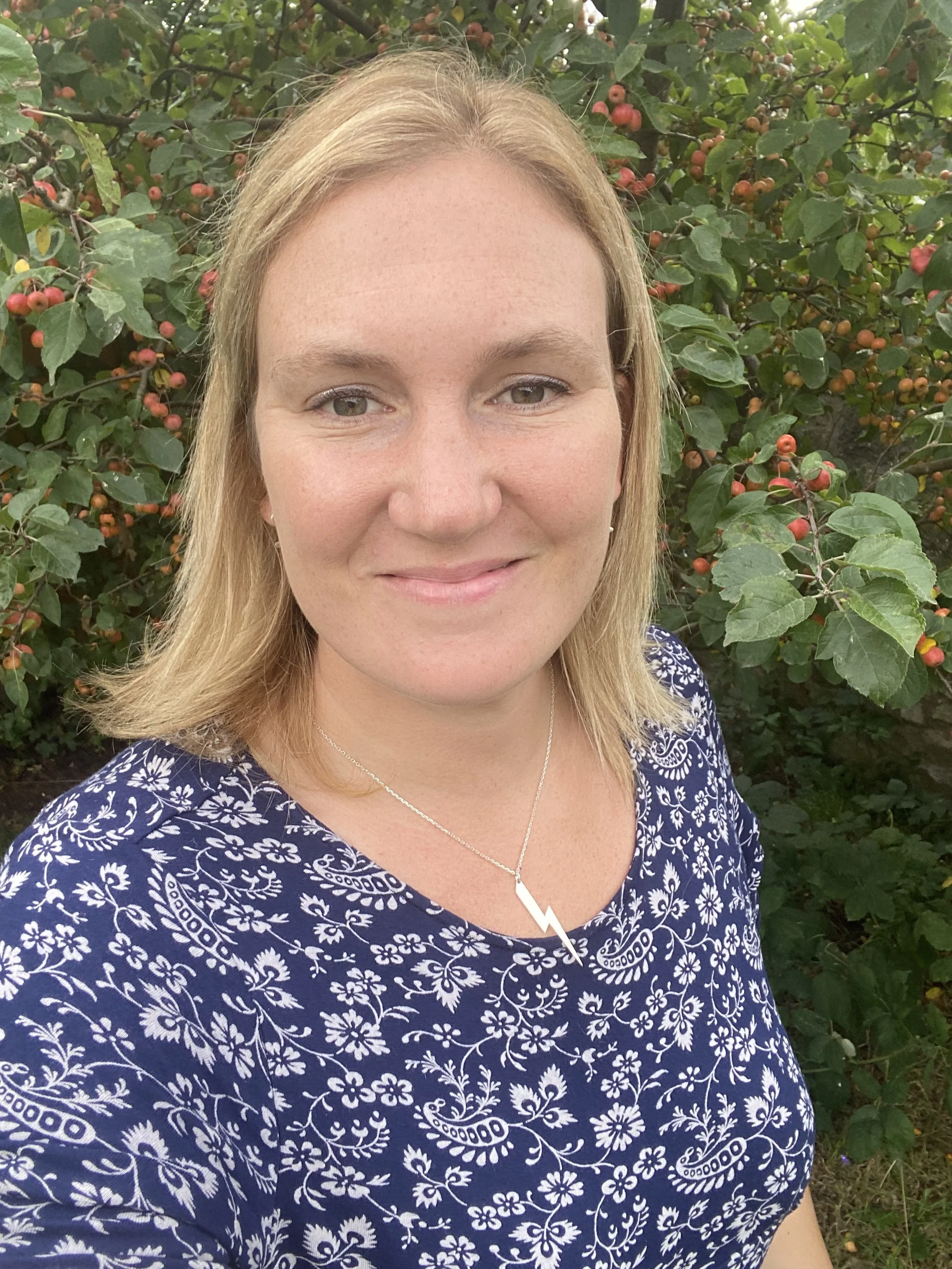 Claire Victoria Bishop stood outside in front of a crab apple tree