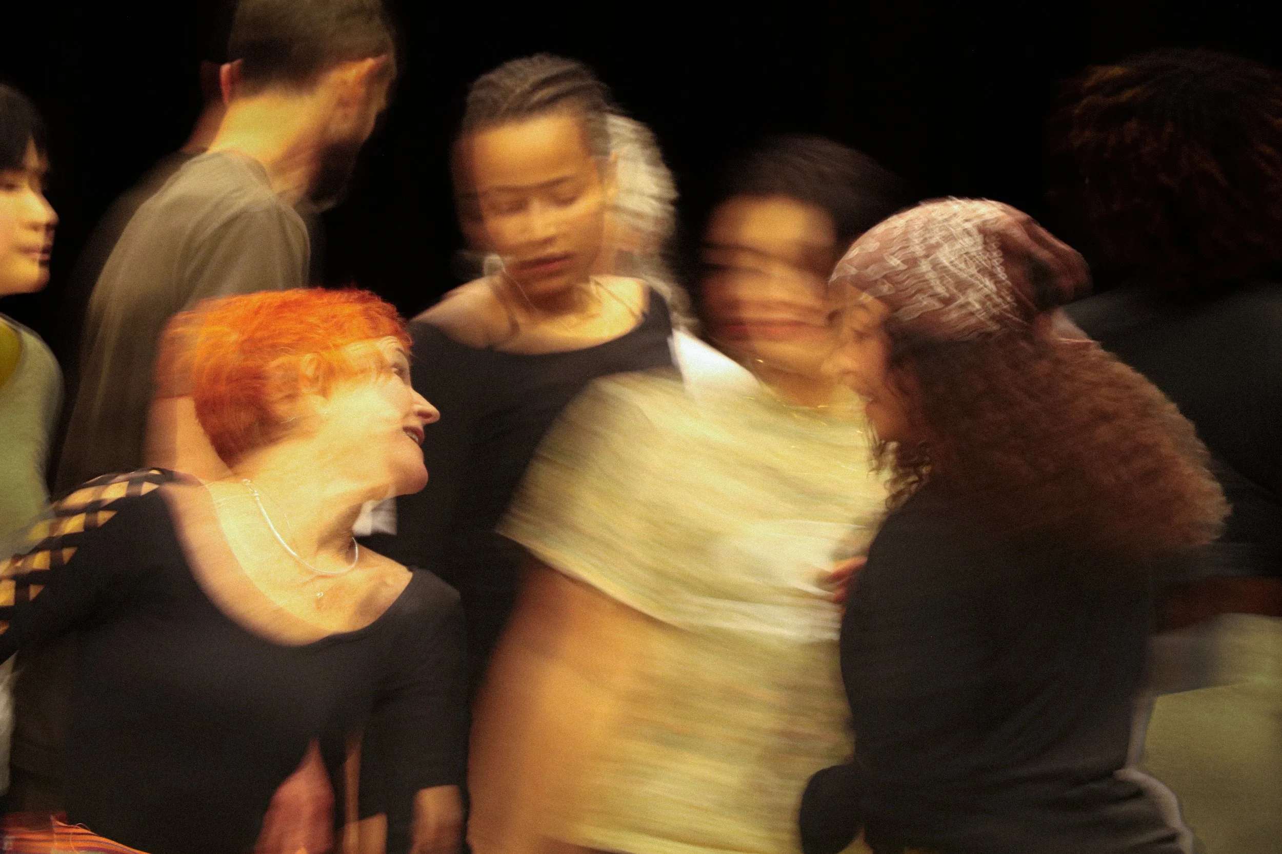 Group of people in motion blur, engaging in conversation or interaction in a dark setting.