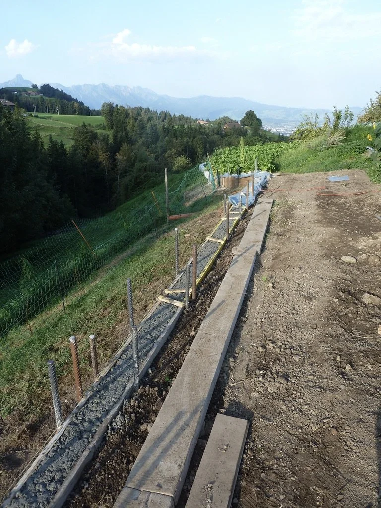 Bau einer kleinen Stützmauer beim Böschungsanfang. Damit der Humus im Garten bleibt