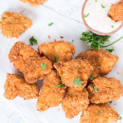 Pezzetti di pollo fritto con salsa e prezzemolo.