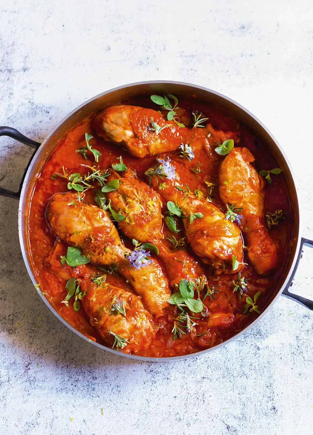 Pollo cacciatore con pomodoro, erbe aromatiche e fiori commestibili