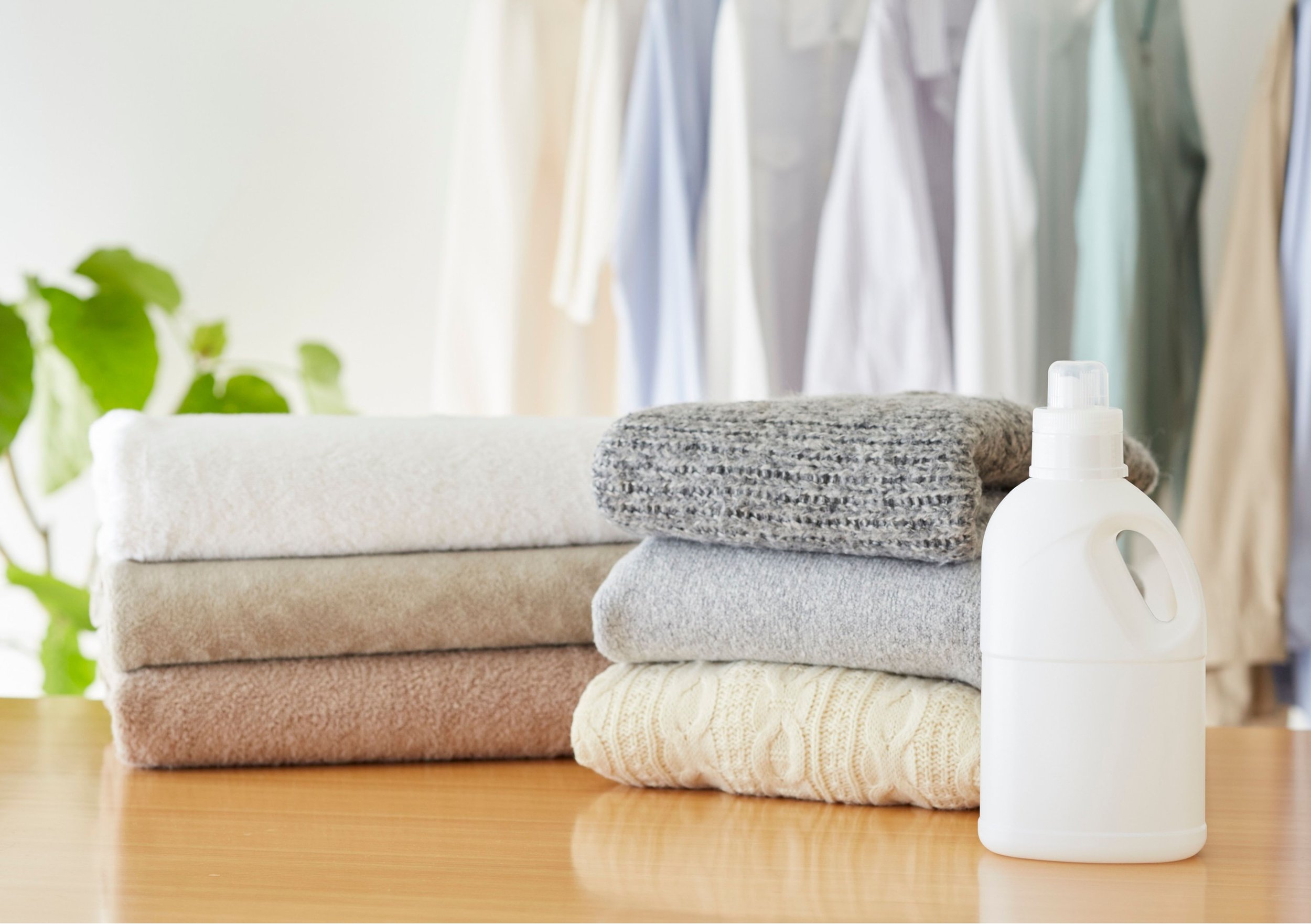 Stack of folded towels next to a bottle of laundry detergent in a laundry room.