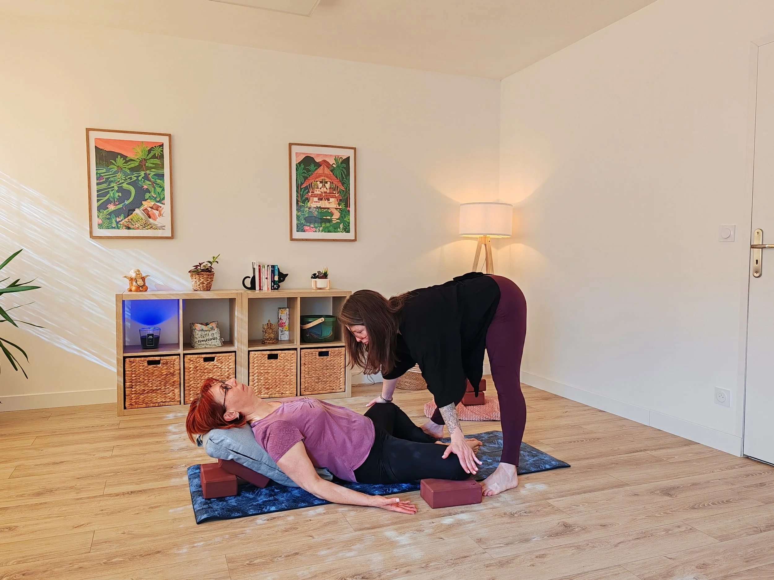 Une femme en train de faire une séance de yoga ou de méditation avec une autre femme dans un salon bien éclairé.