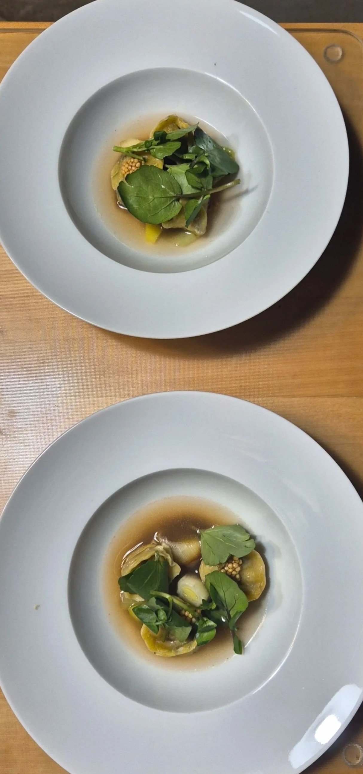 Deux assiettes de raviolis à la sauge, garnies de feuilles de sauge, dans un bouillon clair.