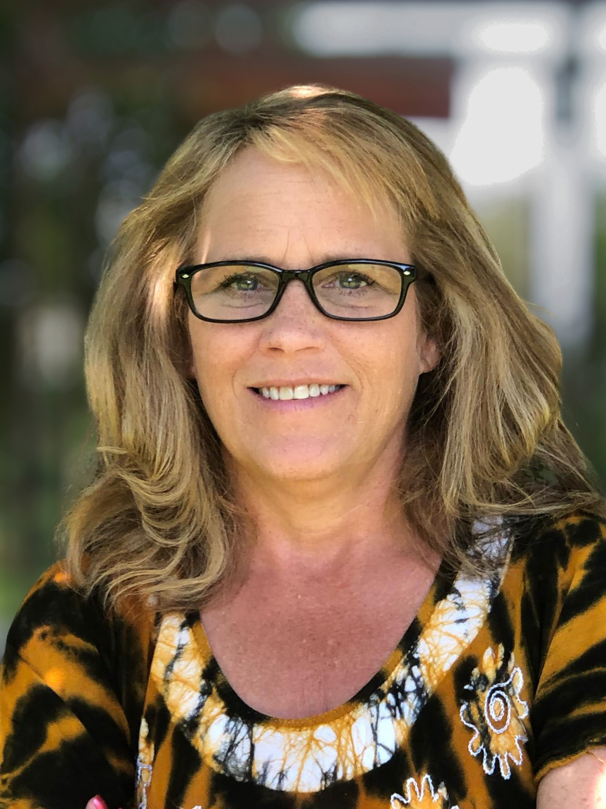 PPAO Practitioner Michele Macfarlane in a yellow and black patterned top over a blurred background