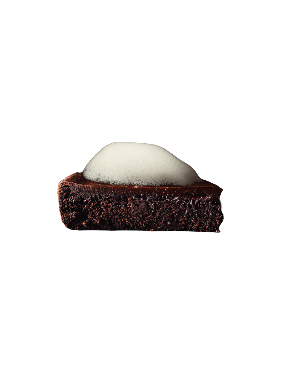 Persona sosteniendo una bebida con una pizza con ingredientes como tomate, queso y hierbas, en un entorno oscuro con ropa roja.