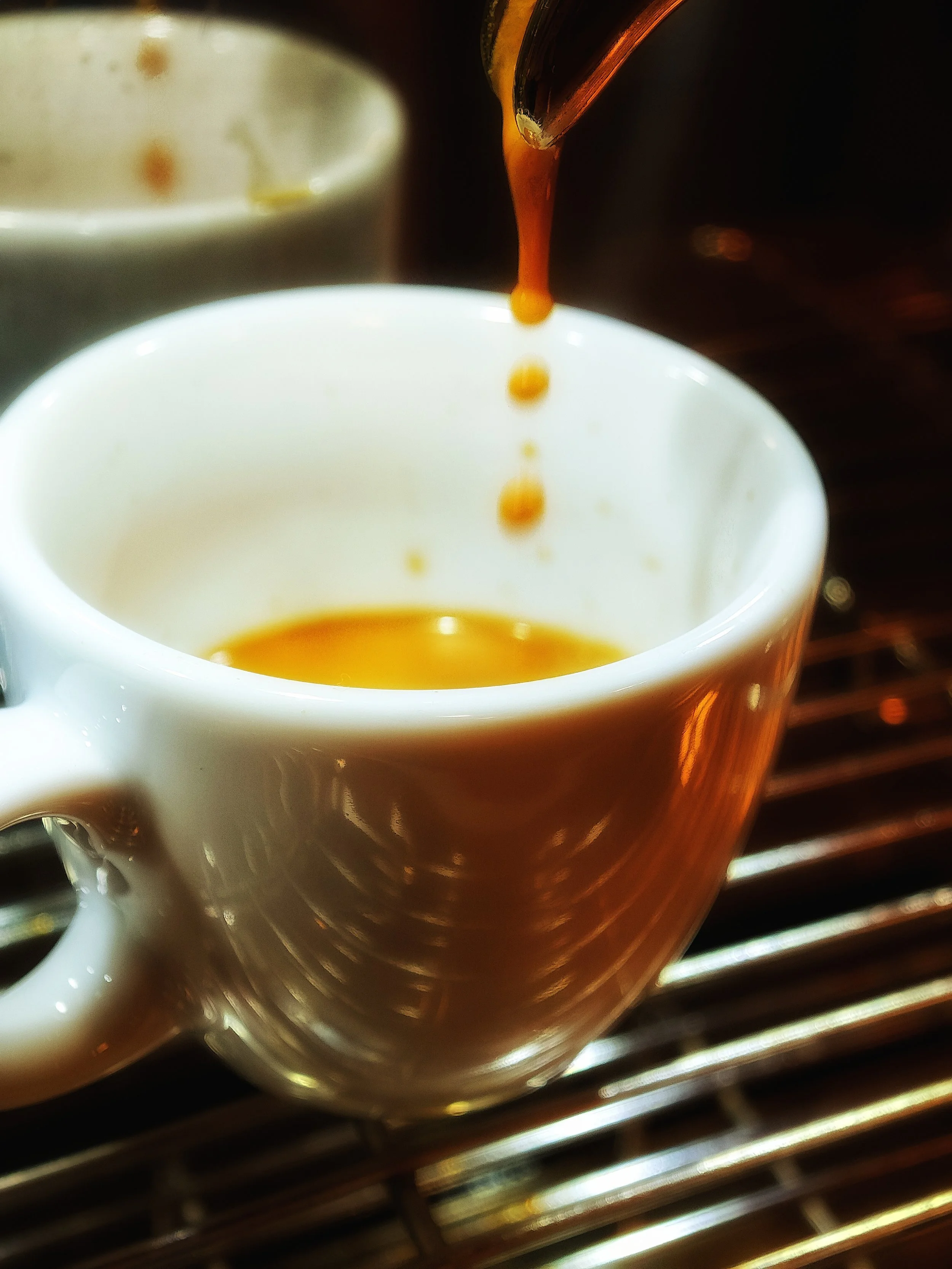 Kaffeetasse, aus der frisch gebrühter Kaffee eingefüllt wird, während der Kaffee direkt aus einer Kaffeekanne gegossen wird.