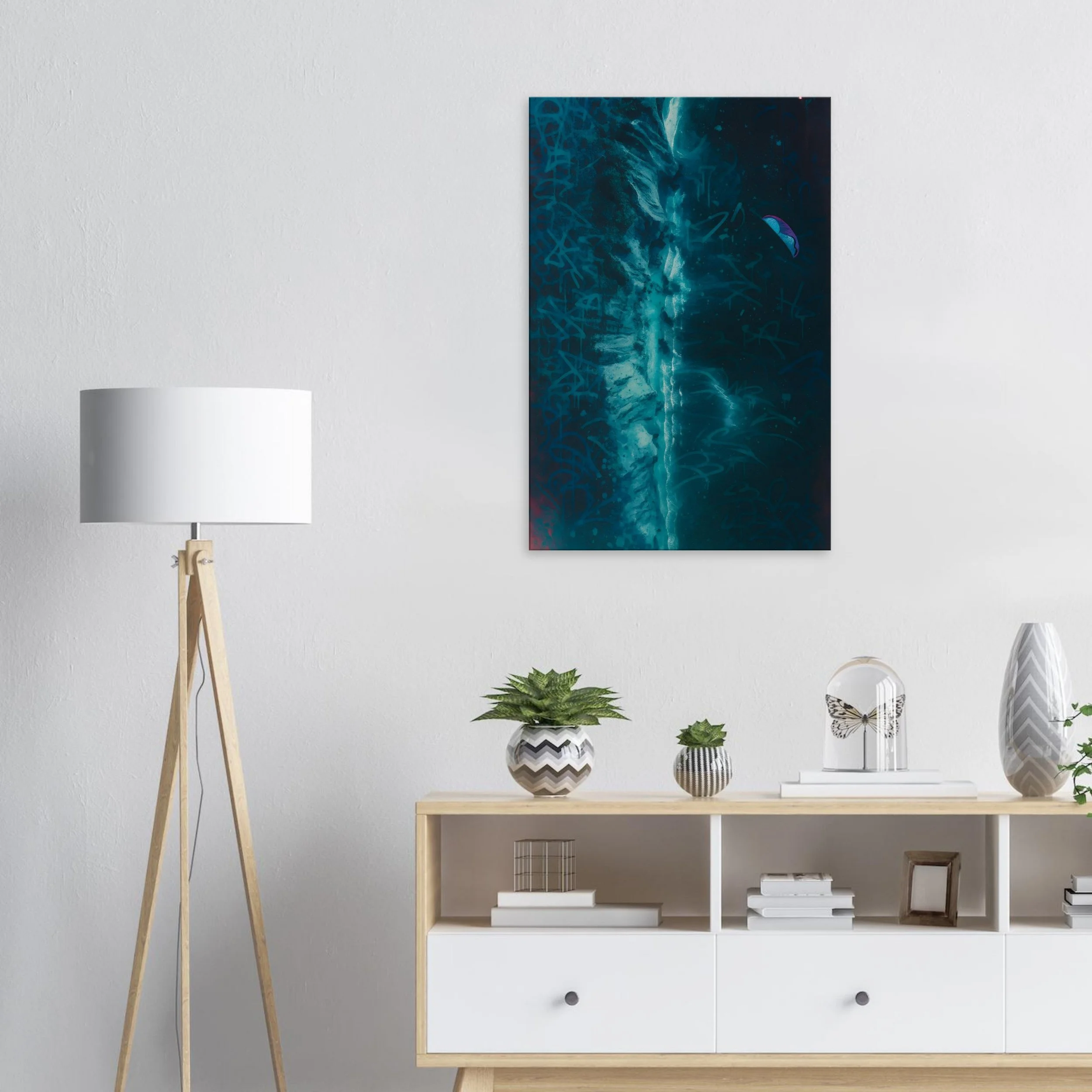 Modern living room with abstract blue artwork on wall, white bookshelf decorated with potted plants, decorative objects, and a tall floor lamp with wooden tripod base.