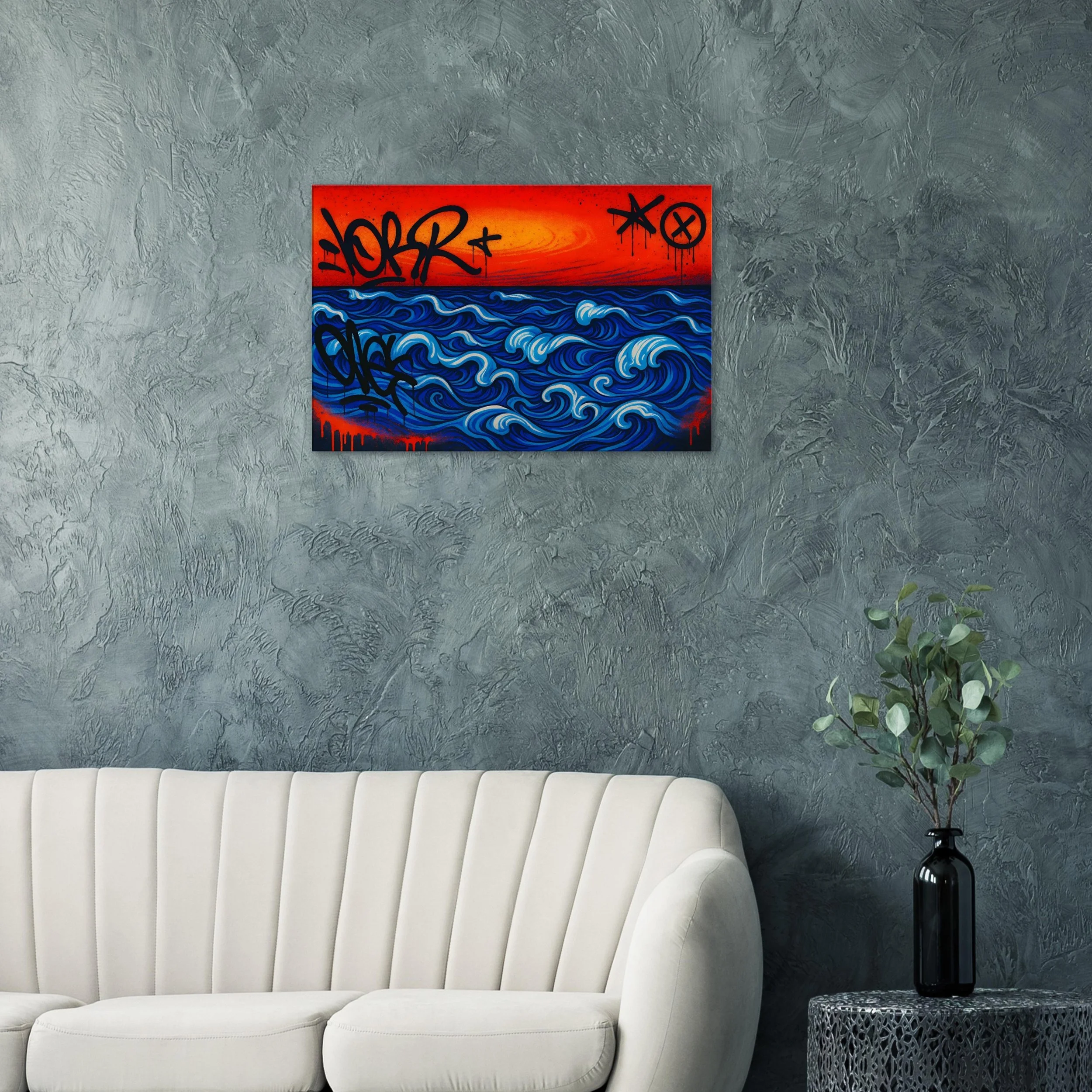 Abstract painting of blue waves with a red sky and graffiti tags on a gray wall above a white couch and a black vase with a leafy green plant.