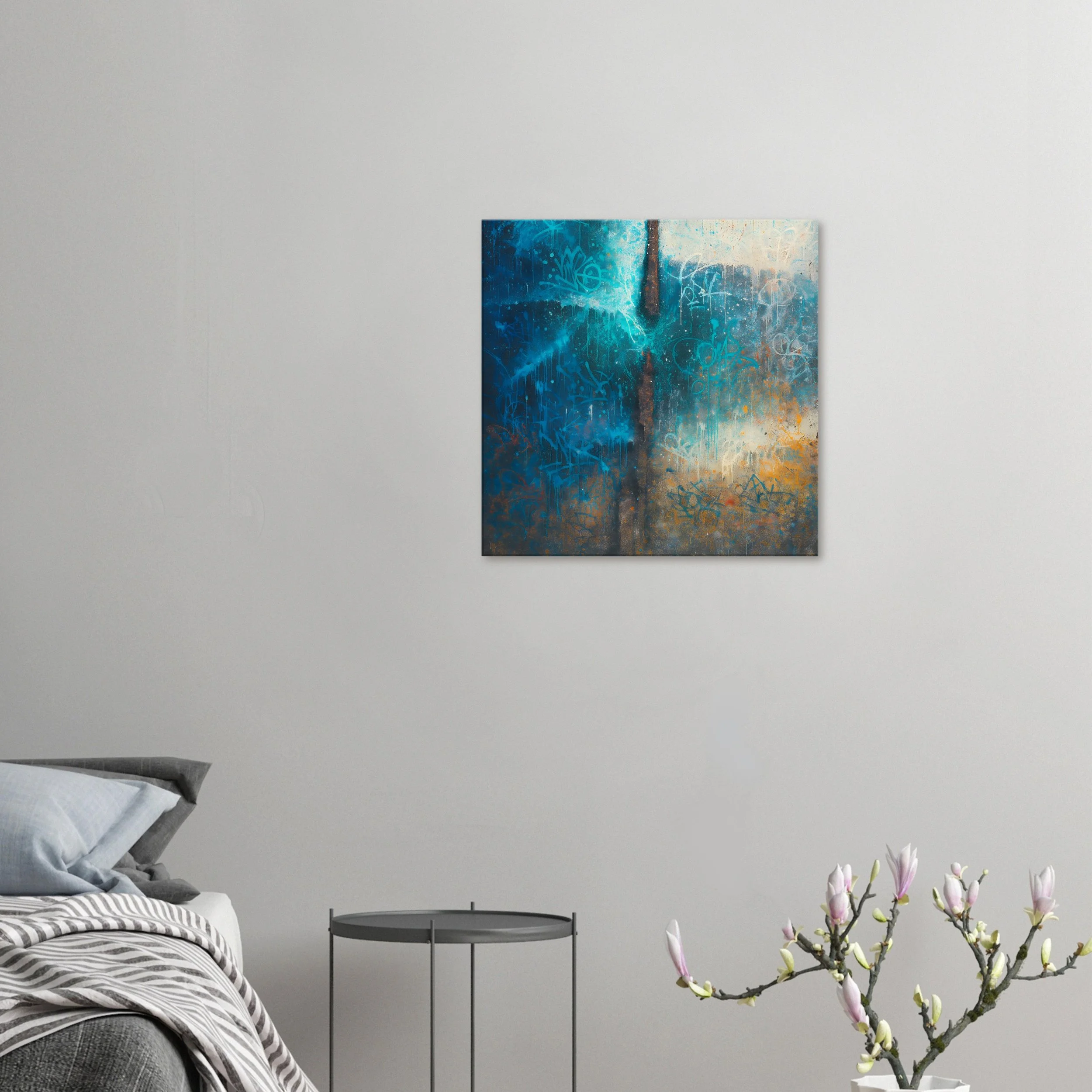 A modern bedroom with a gray bed, a small round black side table, and a white vase with blooming pink flowers; abstract blue and orange artwork on plain white wall.