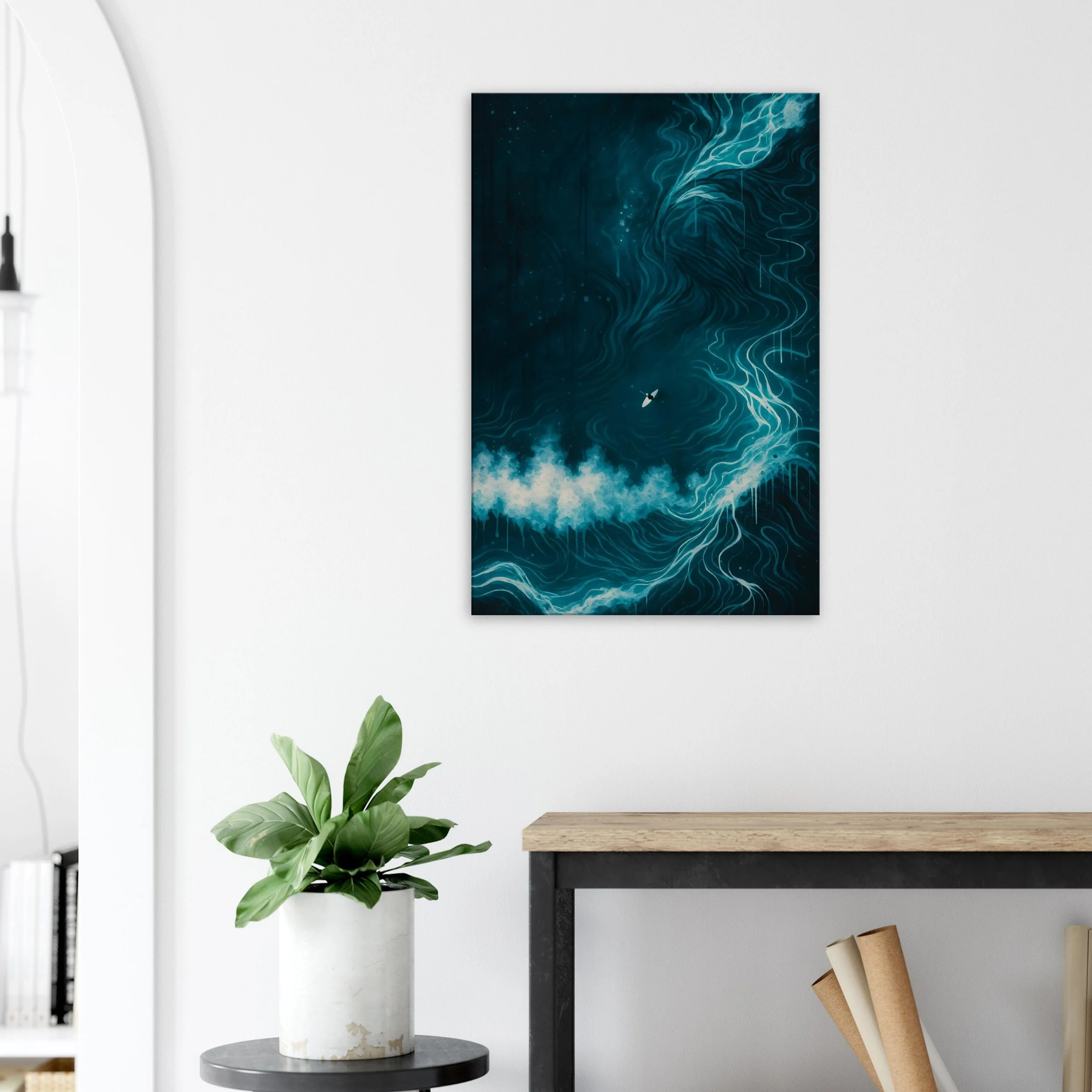 Abstract blue and white swirling ocean-themed artwork hanging on a white wall, with a potted plant on a small table below and a wooden table to the right.
