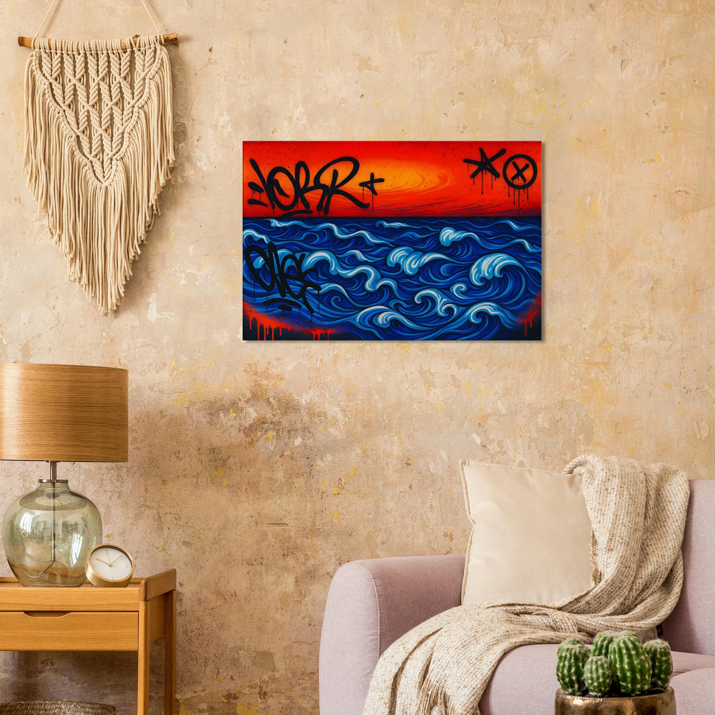 A modern living room with a textured beige wall, a macrame wall hanging, an abstract ocean and sunset painting with graffiti-style text, a wooden side table with a glass lamp and clock, a beige sofa with a cream pillow and a knitted throw, and a cact